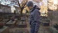 Sad man looking at grave on ancient cemetery, commemorating family, generation