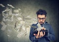 Hipster man looking at his wallet with money dollar banknotes flying out away Royalty Free Stock Photo