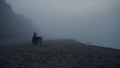 Sad man looking sea landscape in fog. Serious guy sitting on sandy beach Royalty Free Stock Photo