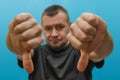 Sad man showing thumbs down on blue background. Royalty Free Stock Photo