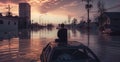 A sad man sits on the roof of his car on a flooded street during sunset. The aftermath of the hurricane in the city Royalty Free Stock Photo