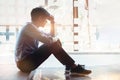 Sad man sitting on the floor by window at office walkway feeling tired frustrated. Depression and anxiety disorder concept