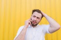 sad man talking on the phone on a yellow background. The man heard the bad news over the phone Royalty Free Stock Photo