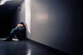Sad man with trauma sitting on floor. Shame, guilt or sorrow. Desperate guy crying in dark corridor. Royalty Free Stock Photo