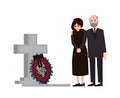 Sad man and woman dressed in mourning clothes standing near grave with tombstone and wreath. Grieving people or Royalty Free Stock Photo