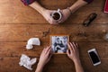 Sad mans, womans hands holding broken picture of romantic couple.