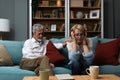 Sad mature woman sitting away from her husband after having quarrel. Senior couple not talking having argue at their home. Royalty Free Stock Photo