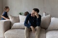 Tired pensive man sit on sofa fatigued due noisy kids Royalty Free Stock Photo