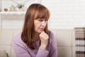 Sad middle age woman sitting on a sofa in the living room. Menopause