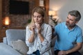 Sad middle aged european man calms crying female, got bad news in living room interior