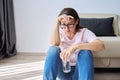 Sad middle aged woman sitting at home on the floor with glass of water Royalty Free Stock Photo