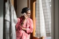 Sad upset African man having difficult conversation on phone, standing by window at home Royalty Free Stock Photo