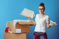 Sad modern woman near cardboard box with broken dish on blue Royalty Free Stock Photo