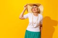 Sad mood. Elegant senior woman in summer style outfit and hat isolated on bright yellow background. Concept of beauty Royalty Free Stock Photo