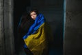 Sad mother hugging her son, both wearing Ukrainian national colors on black background