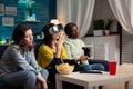 Sad nervous women friends sitting on couh playing online videogames using vr headset and joystick
