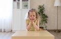 Sad, offended little girl is sitting at the table and looking down. Royalty Free Stock Photo