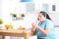 Sad overweight woman with donuts in kitchen