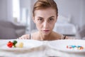 Sad pale woman standing in front of plates