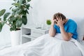 sad patient in medical gown touching head in hospital.