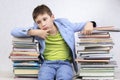 Sad pensive boy student sits between stacks of books Royalty Free Stock Photo