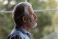 Sad senior 70s man lost in thoughts looking out window Royalty Free Stock Photo