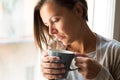 Woman holding a cup of coffee portrait next to a window