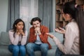 Sad pensive young caucasian man and black female listened to psychiatrist in clinic interior