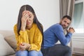 Sad pensive young girl thinking of relationships problems sitting on sofa with offended boyfriend, conflicts in marriage, upset Royalty Free Stock Photo