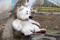 A sad plush toy of a white dirty big teddy bear, lost and forgotten. Bear alone on the ground. Love expectation concept Royalty Free Stock Photo