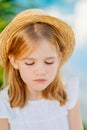 sad portrait of a little girl with blonde hair in a straw hat. children's whims