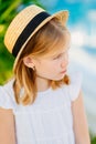 sad portrait of a little girl with blonde hair in a straw hat. children& x27;s whims