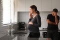 Sad pregnant woman and husband contemplating in kitchen