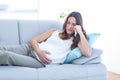 Sad pregnant woman lying on sofa