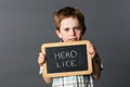Sad preschool kid protecting from head lice behind school slate Royalty Free Stock Photo