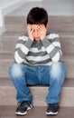 Sad preteen sitting on the stairs at home