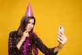 pretty young woman wearing pink party hat and boa around her neck looking at her smartphone with sad face Royalty Free Stock Photo