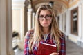 Sad puzzled young girl teenager student with glasses holding a book with an unhappy sad expression. Royalty Free Stock Photo