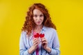 Sad redhaired ginger curly cry female tearing up red broken paper heart in studio yellow background..sex education