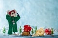 Sad Santas Helper Elf With Head in Hands Standing Next to a Broken Christmas Bauble. North Pole Christmas Scene. Santas Workshop. Royalty Free Stock Photo