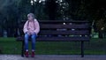 Sad school girl sitting on bench in park, lost missing kid, waiting for parents Royalty Free Stock Photo