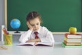 Sad schoolgirl looks at a book while sitting in class. A math problem in a child at school Royalty Free Stock Photo