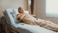 Sad senior Asia man having having heart attack lying on hospital bed and press emergency button. Sick aged guy lying hospitalized Royalty Free Stock Photo