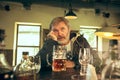 The sad senior bearded male drinking beer in pub