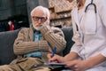 Sad senior man looking at doctor writing down