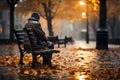 Sad senior man sitting alone on a bench in city park on autumn day. Elderly man enjoying nice fall weather Royalty Free Stock Photo