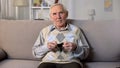 Sad senior man sitting on sofa showing empty wallet on camera, credit poverty Royalty Free Stock Photo