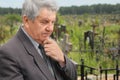 Sad senior standing on cemetery, hand on chin Royalty Free Stock Photo