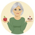 Sad senior woman choosing between chocolate layer cake and apple for dessert