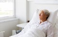 Sad senior woman lying on bed at hospital ward